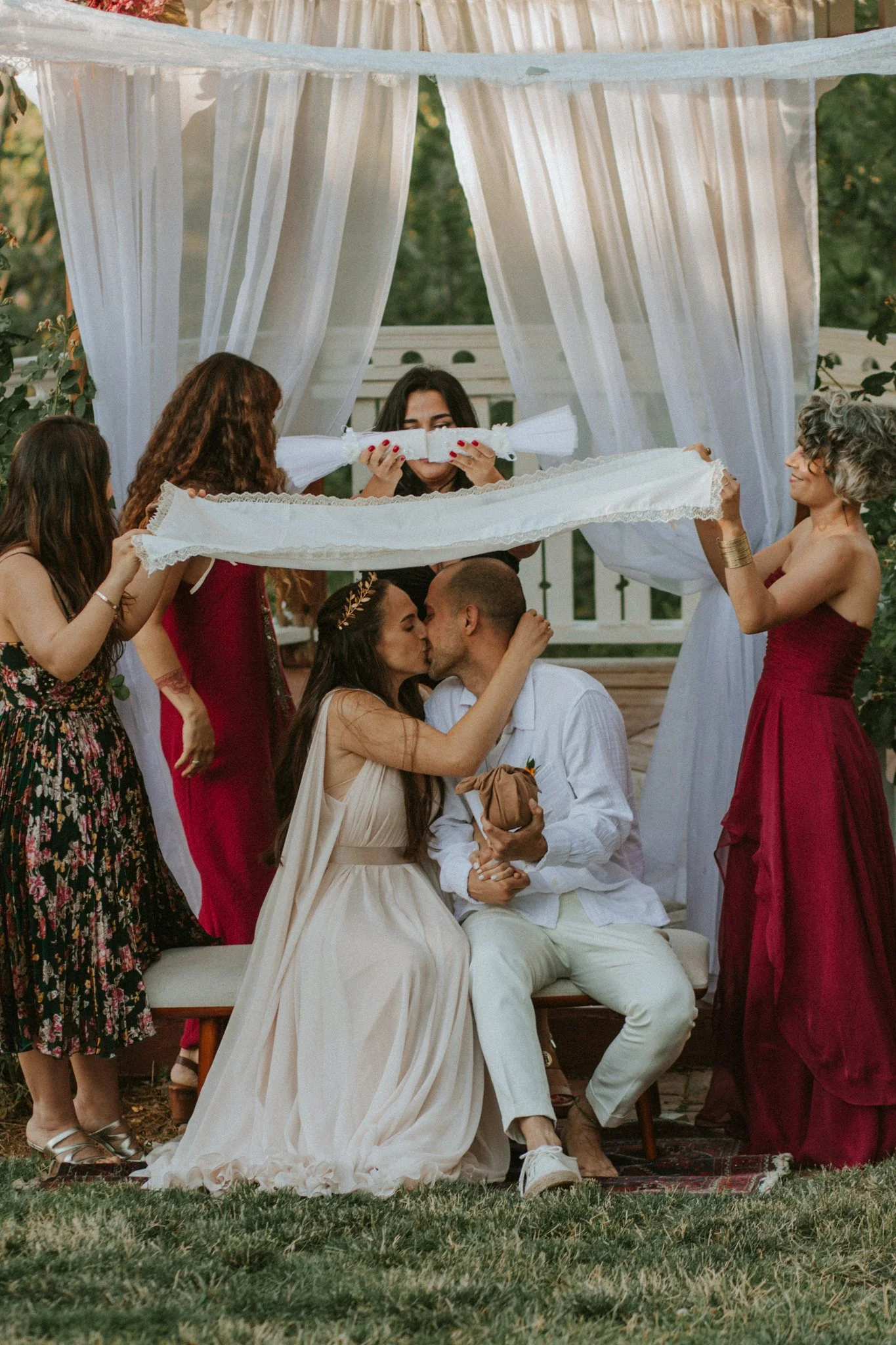 wedding day - the newly weds kissing under the canopy being held by their closest people