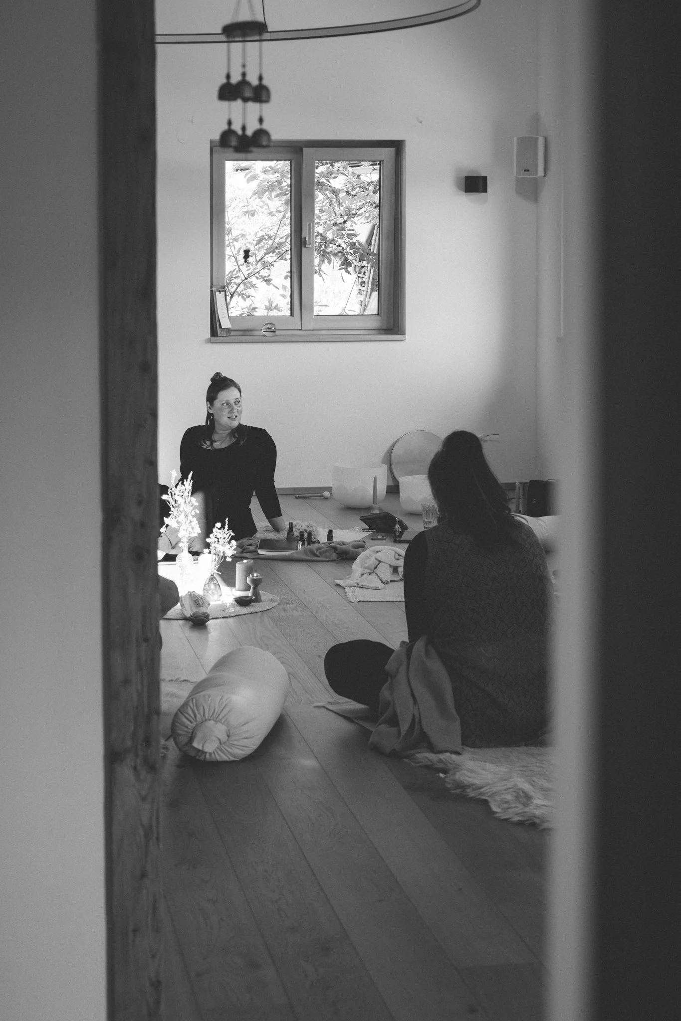 retreat photography - A black and white photo of three women sitting on the floor in a cozy room with wooden flooring.