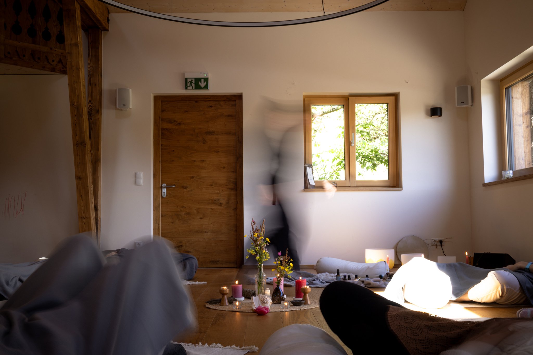 retreat photography - People sitting on the floor in a cozy living room with candles, flowers, and spiritual symbols, possibly participating in a meditation or spiritual practice.