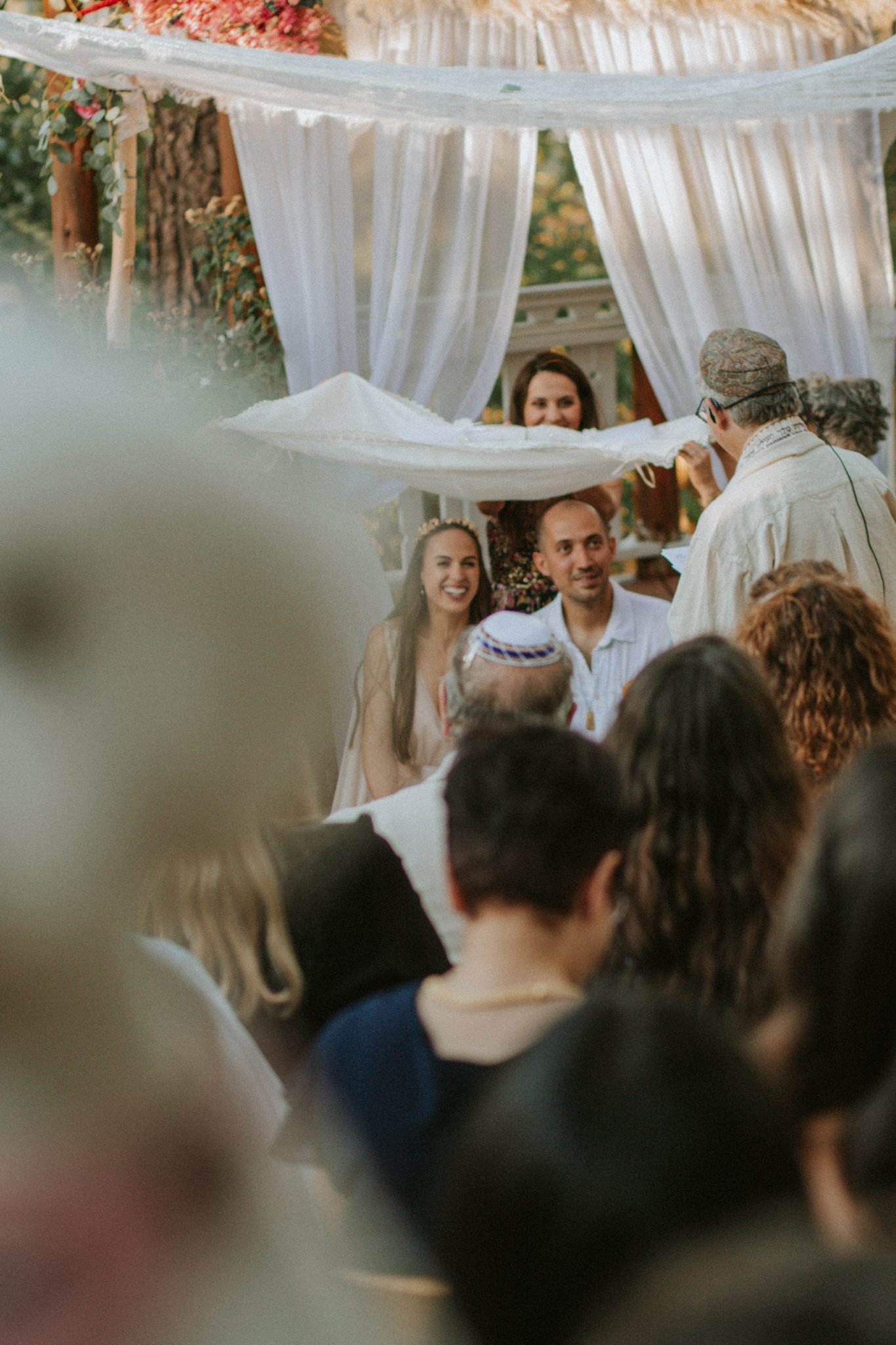 wedding day - couple sitting under a canopy with four open sides. It represents the new home the couple will build together, open to guests and grounded in spiritual ideals