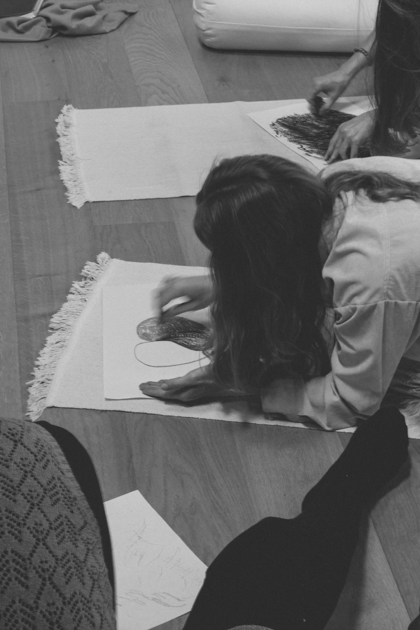 retreat photography - A woman sitting on the floor, drawing and coloring on paper with markers, in black and white.