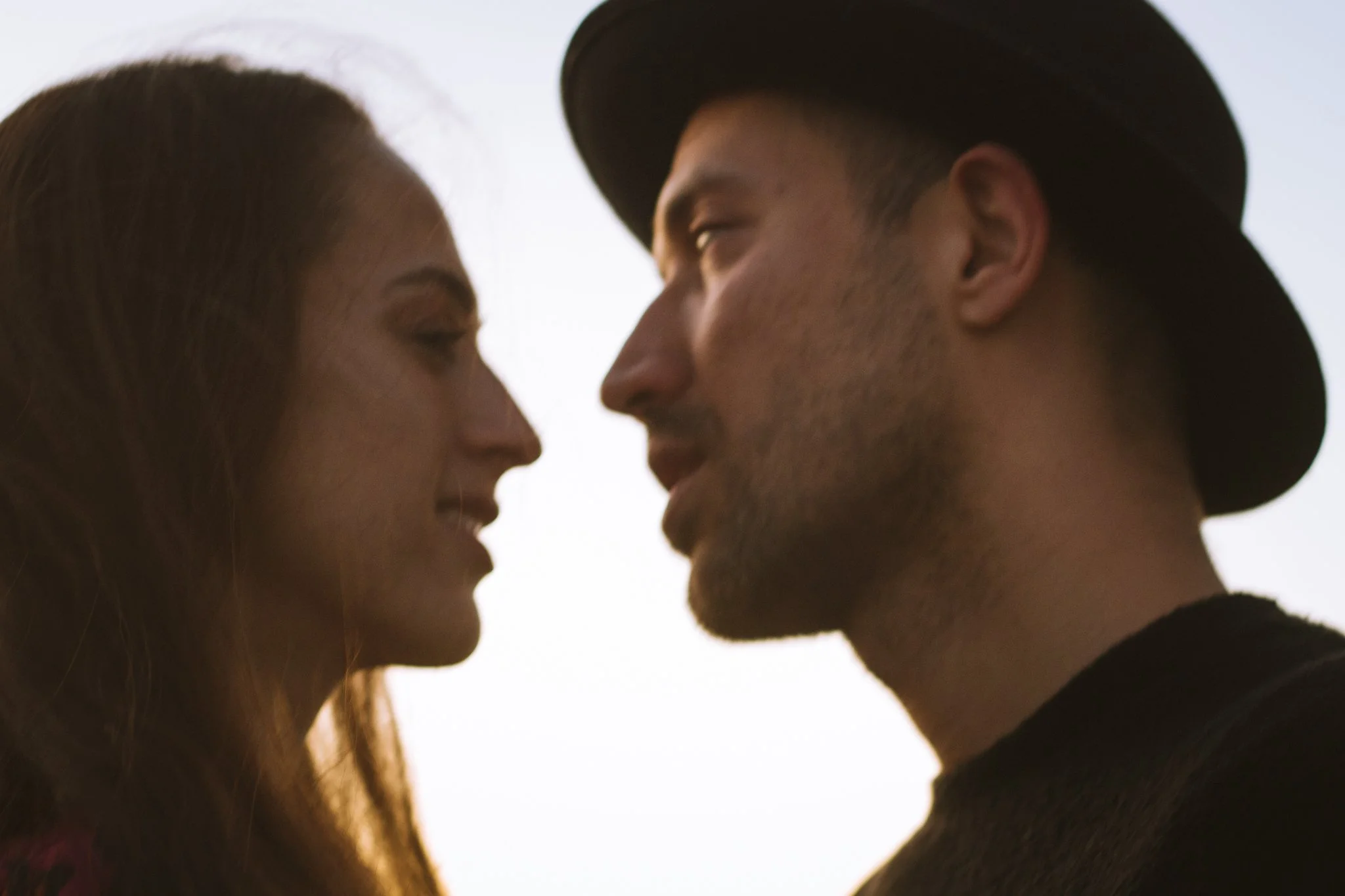 couples photoshoot - Close-up of a man and a woman facing each other with their foreheads touching, smiling, with a bright white background.