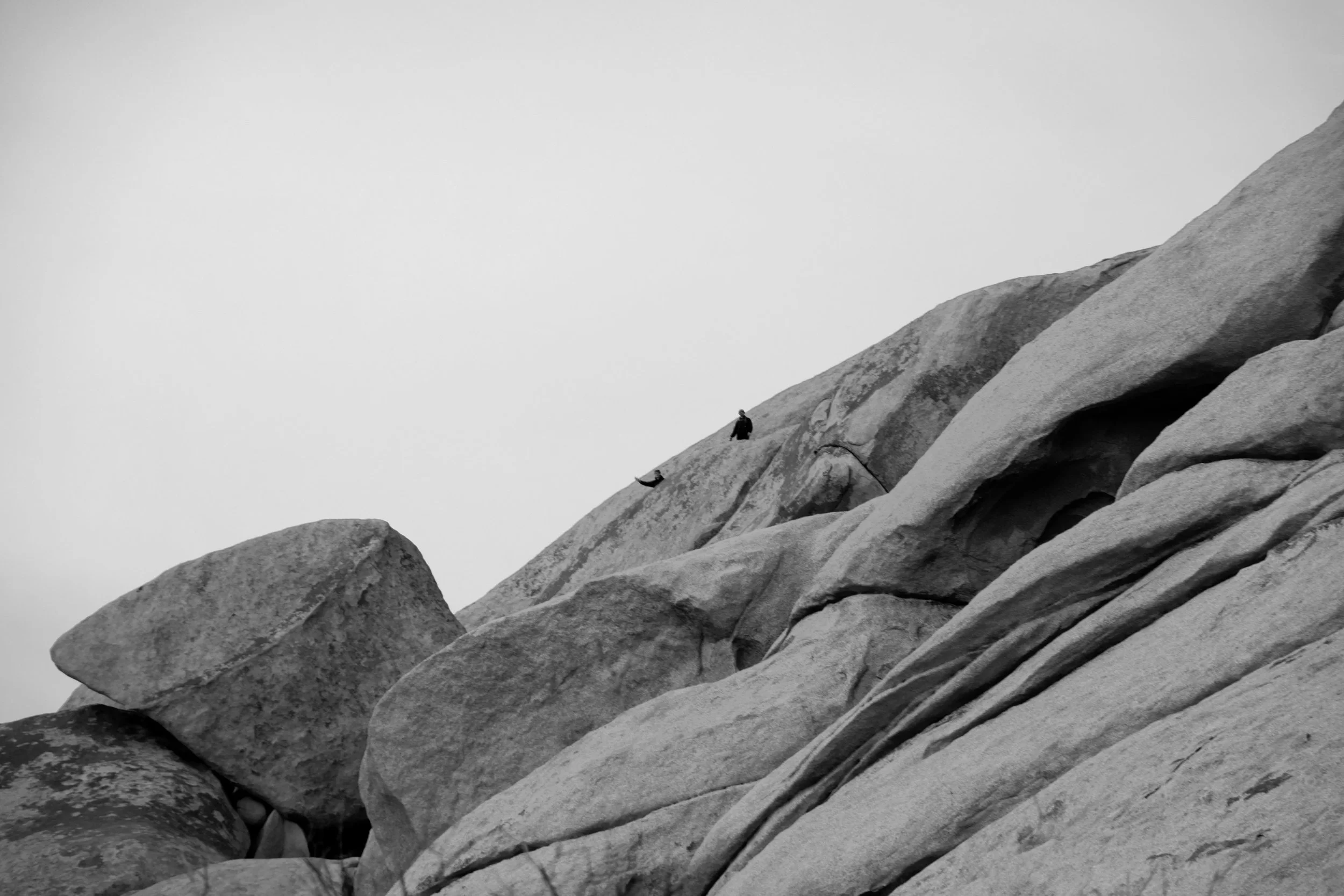 Dripstone: Two friends wave down after climbing the steep rocks in Joshua Tree