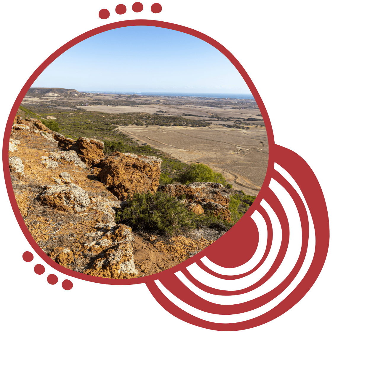 A view from a rocky cliff overlooking an expansive arid landscape with sparse vegetation under a clear blue sky.