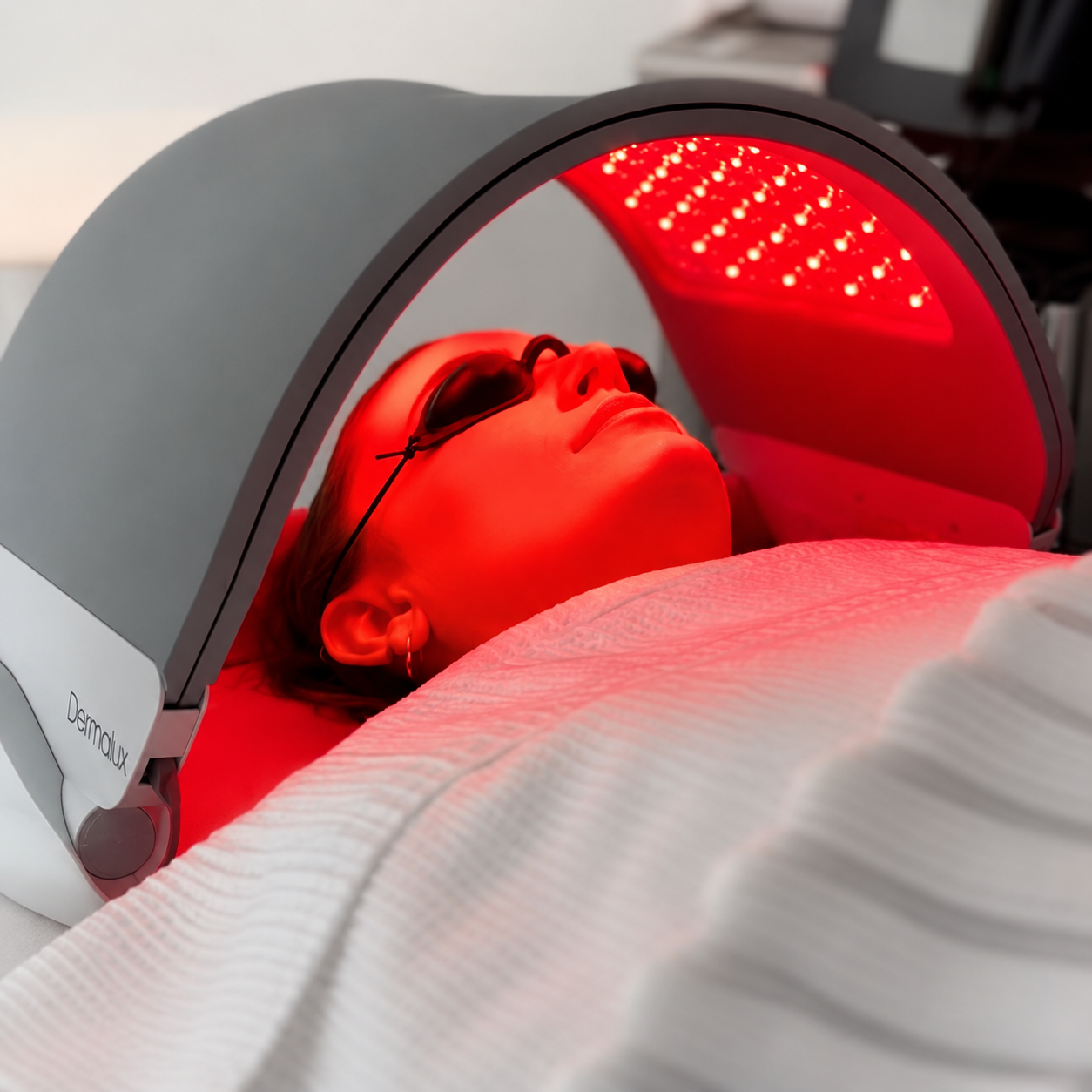 A person lying down with facial cream applied to their face, being massaged or treated in a spa or skincare setting.