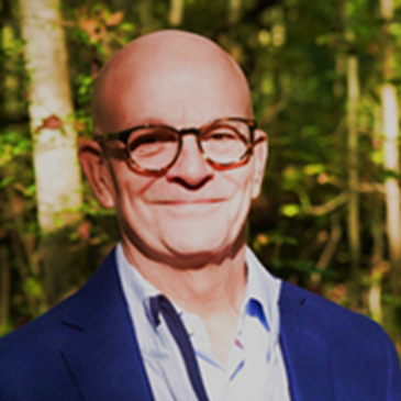 Middle aged smiling with tortoise glasses and a blue blazer