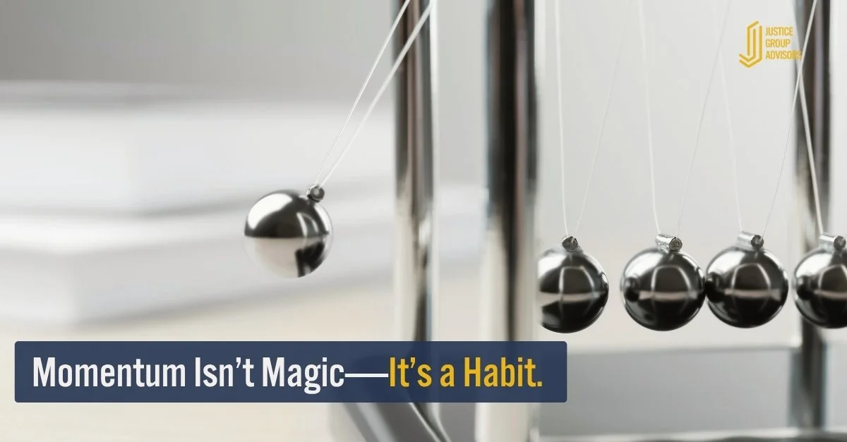 Newton’s cradle in motion, symbolizing momentum. Text overlay reads: “Momentum Isn’t Magic—It’s a Habit.” Justice Group Advisors logo appears in the corner.