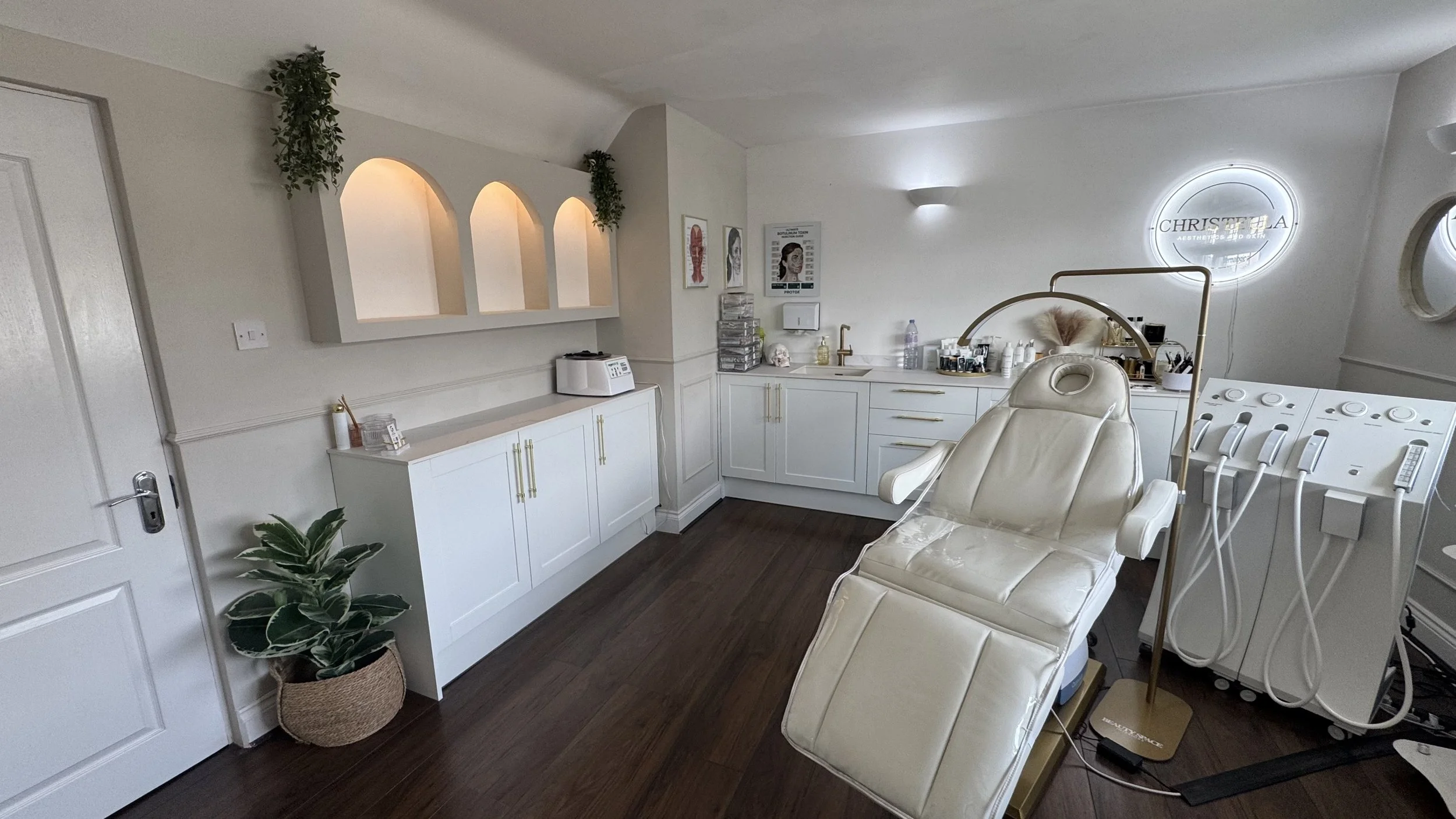 Medical treatment room with white cabinetry, a treatment chair, and medical equipment, including a stool and ultrasound device.