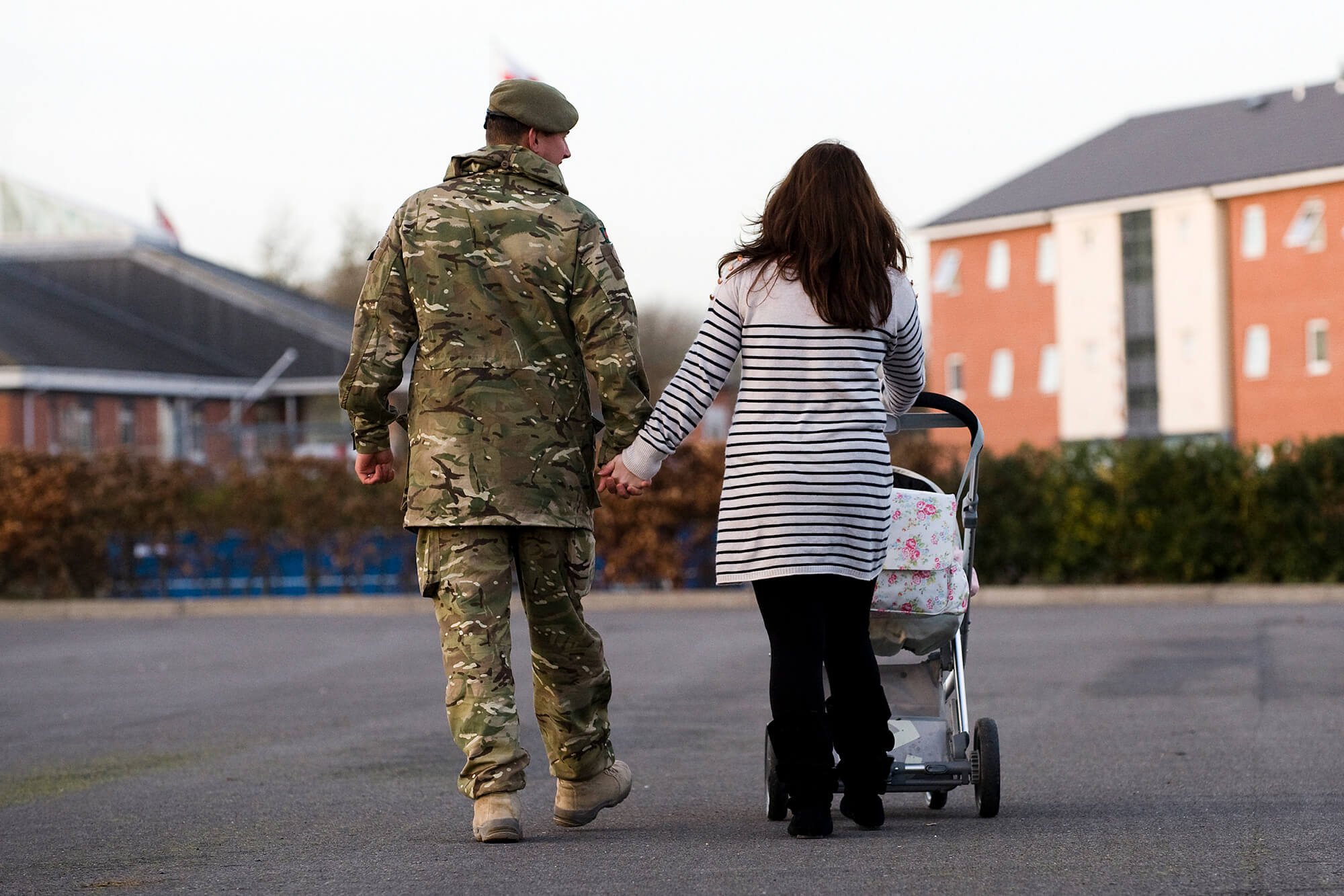 An Army Military Family walking across a car park and a military camp
