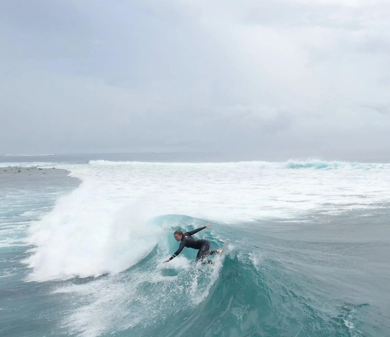 Surfer riding a wave on a cloudy day