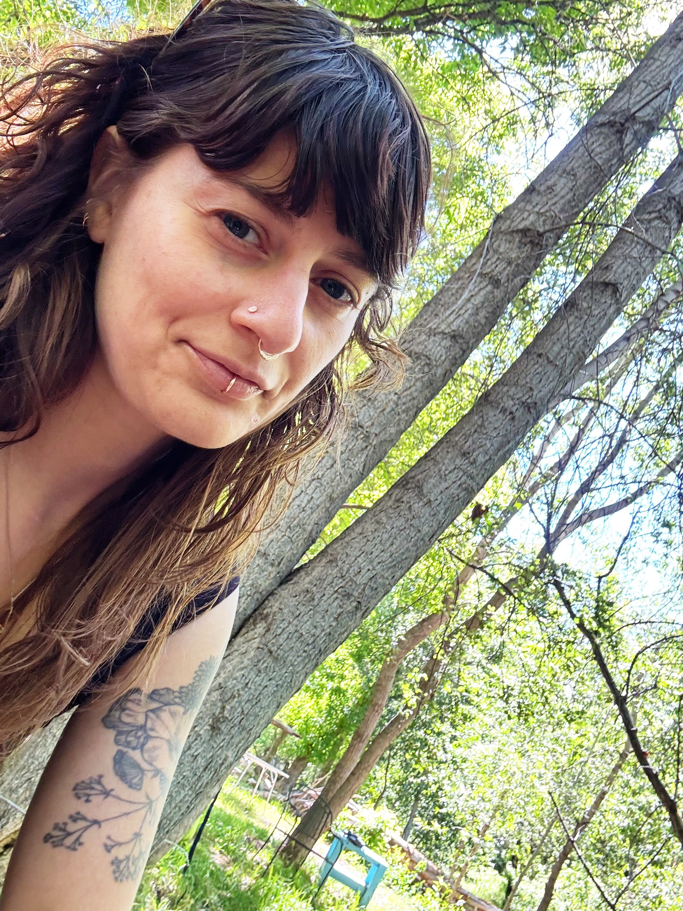 creo therapy studio queer non binary arielle rothenberg art therapist piercings and tattoos smiling person in the woods nature of santa fe wilderness new mexico hiking and enjoying being outside and smiling