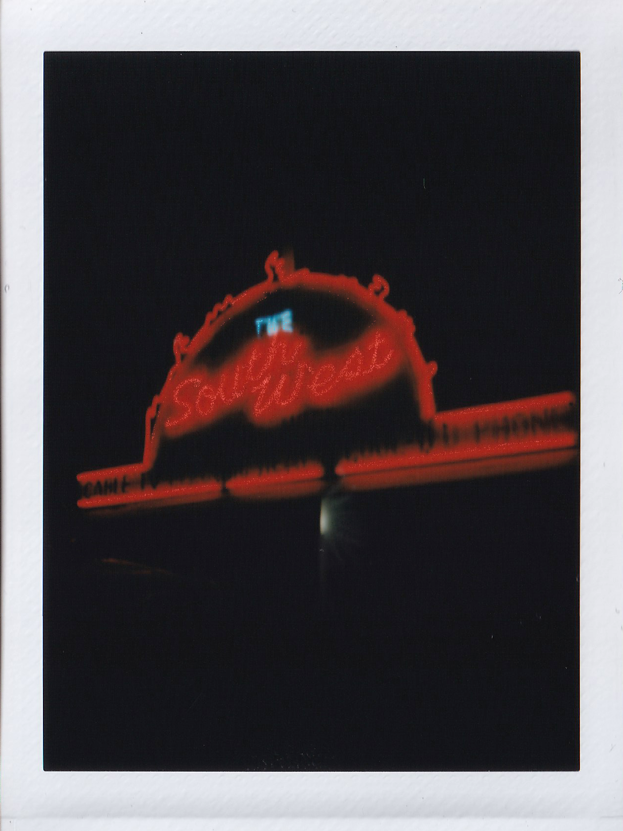 Neon sign for the Southern Hotel, illuminated with red and blue lights, against a dark night sky.
