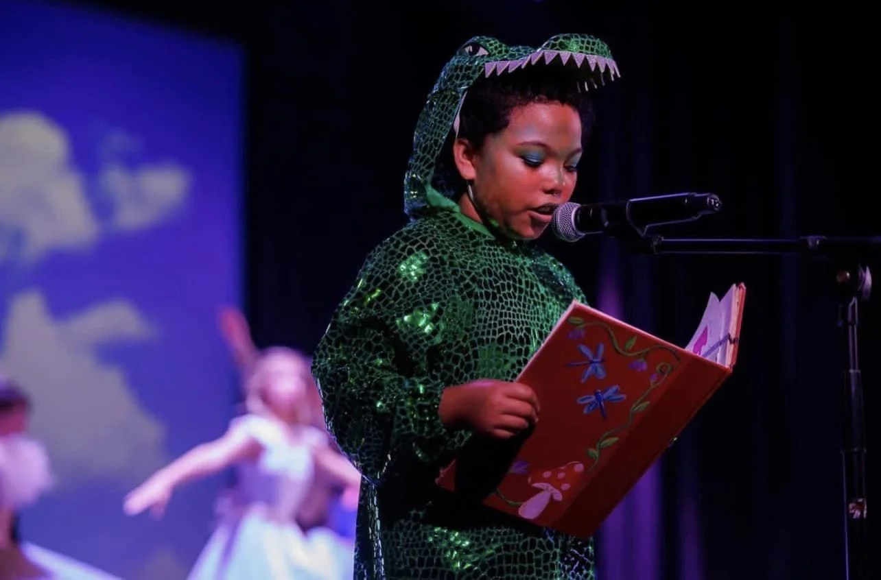 Young Black performer reading on stage in costume