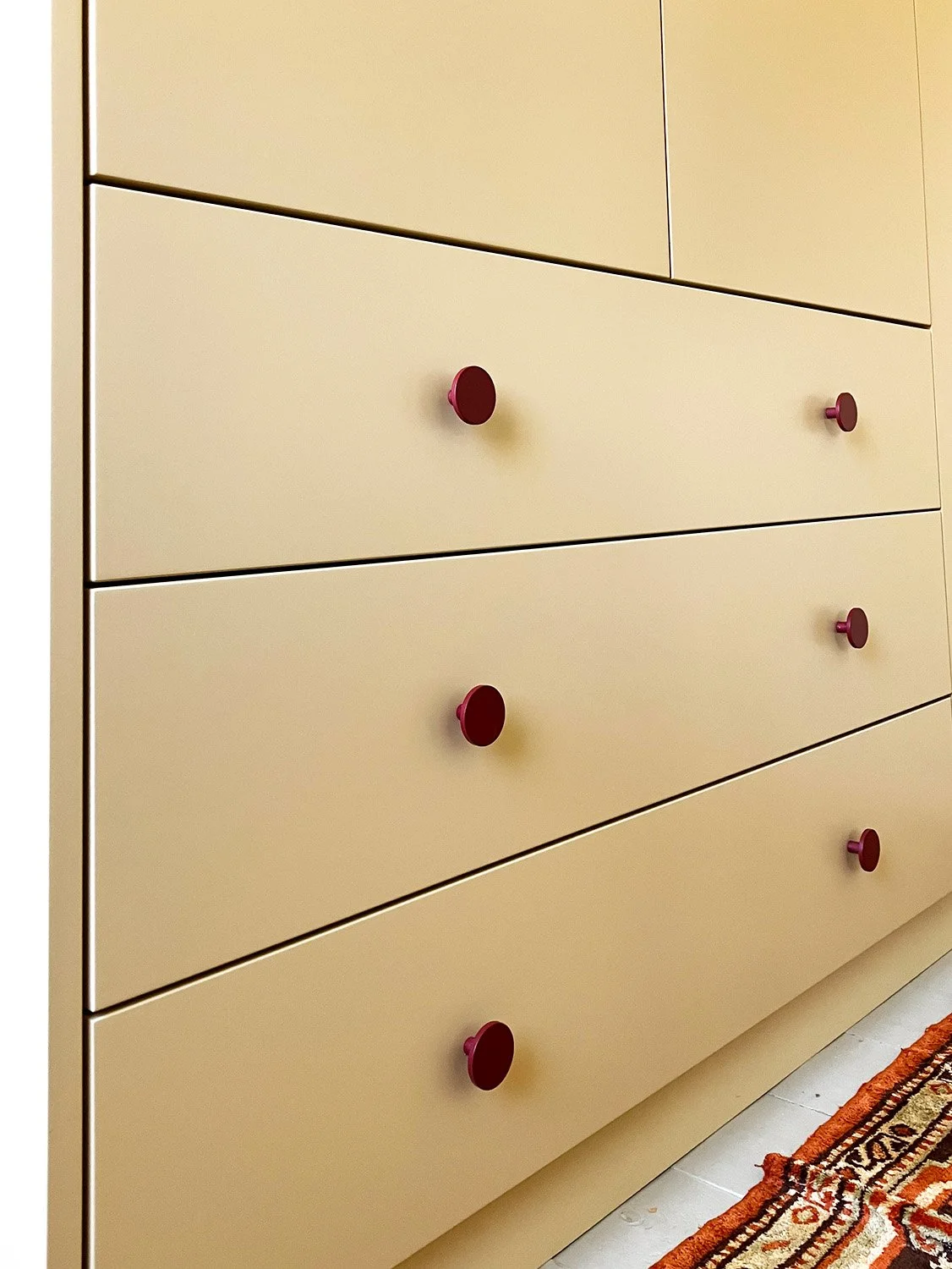 Wide, low built-in drawer unit in ivory colour with rusty red handles in Camberwell, London