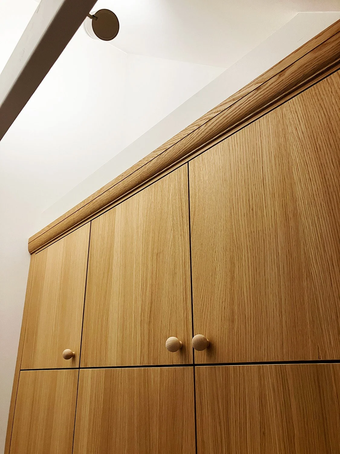 Close-up view of the subtle decorative oak pelmet at the top of the wardrobe in Camberwell, London