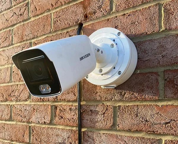 Close-up of a red security camera mounted on a red wall.