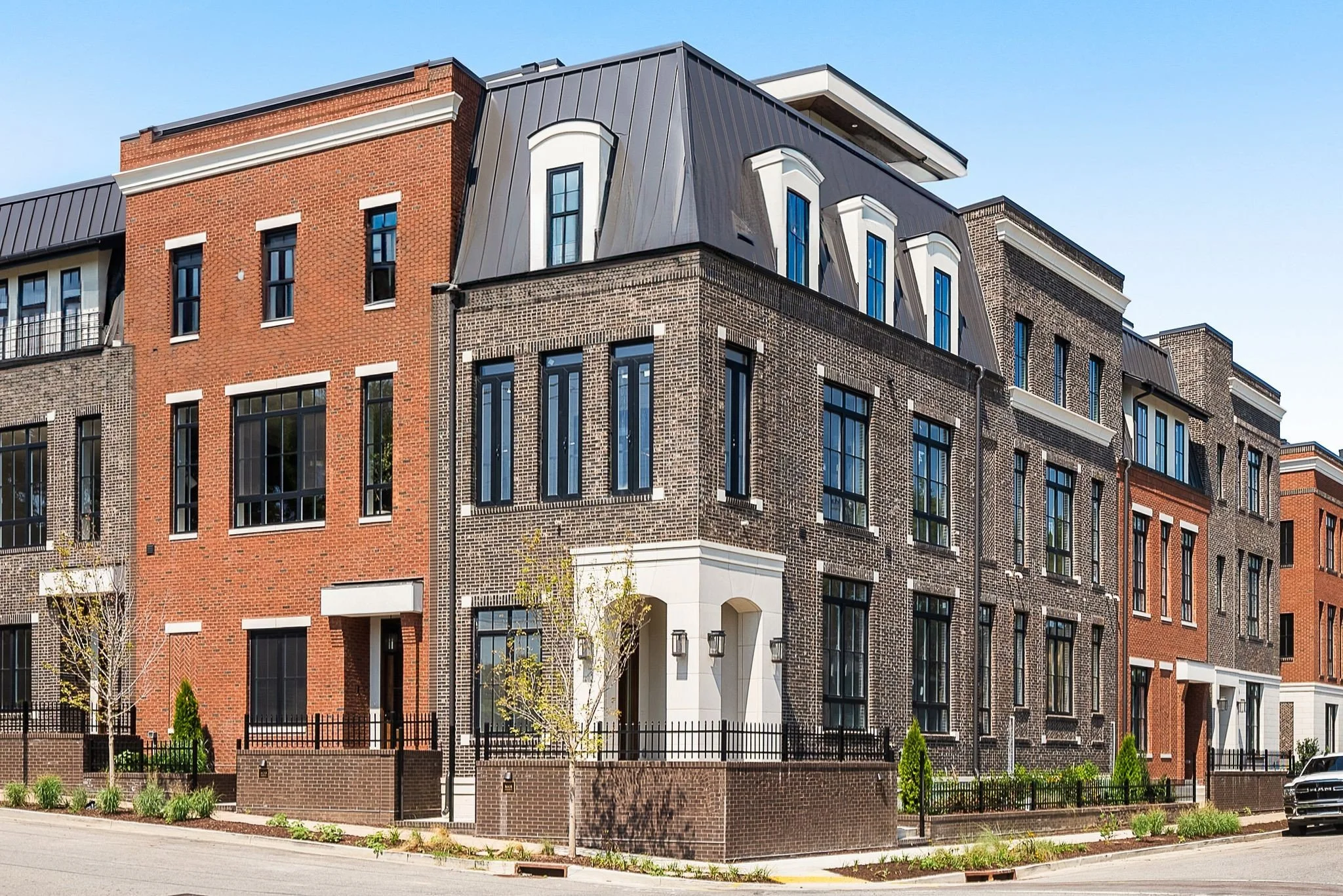 Kitchen with wooden cabinets, white marble backsplash, a countertop with decorative items, and large windows showing a partly cloudy sky and trees outside.