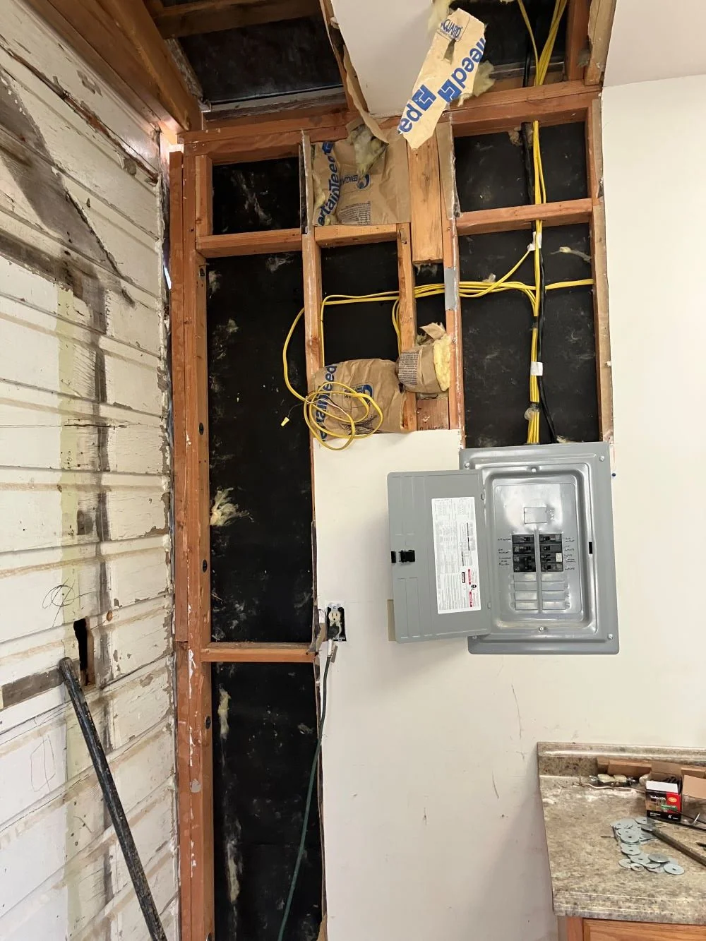 Photo of wall framing with electrical lines and the main panel