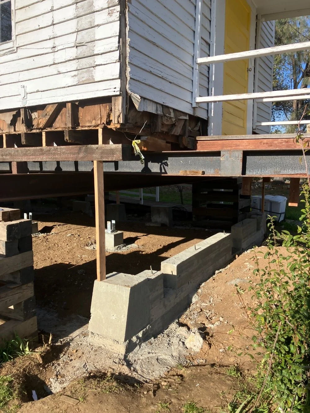 Picture of building corner jacked up on steel girder with concrete foundation wall below.