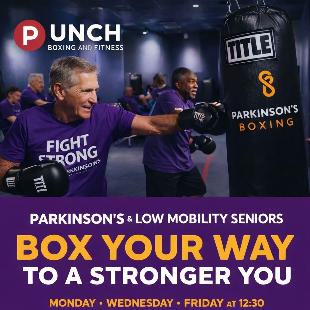 Older man boxing with a trainer at a Parkinson's and low mobility seniors fitness class at Punch Boxing and Fitness gym. Participants in purple shirts, punching a bag in a gym setting.