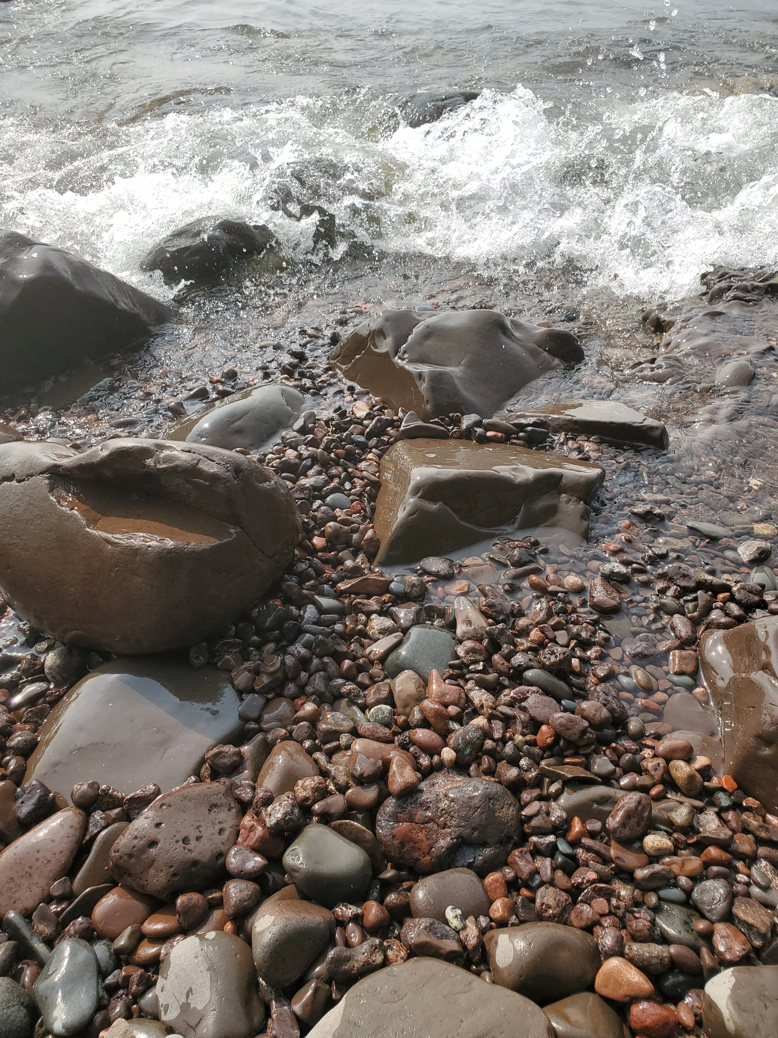 Close-up of a rocky shoreline where waves are gently hitting the stones and pebbles at Cut Throat Creek, MN