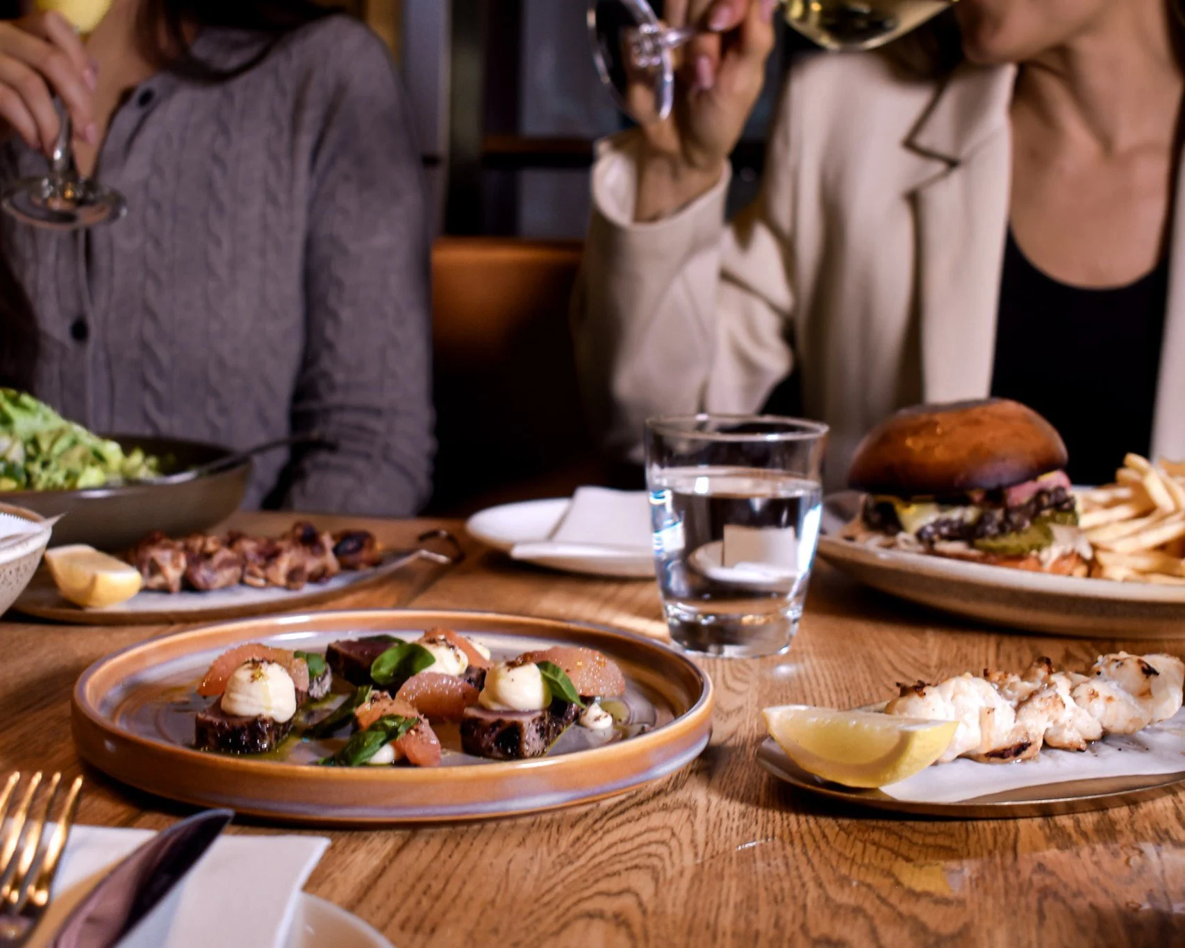 Two guests enjoying lunch and wine over shared plates in the dining room