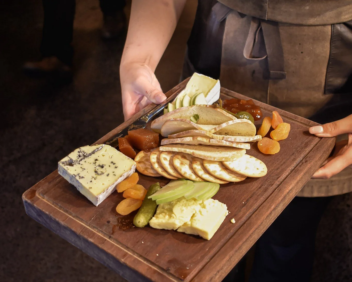 Staff member carrying a cheese and charcuterie grazing board for a group booking