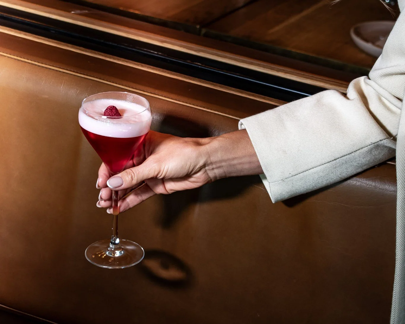 Clover Club gin cocktail being held inside The Glass Goose bar