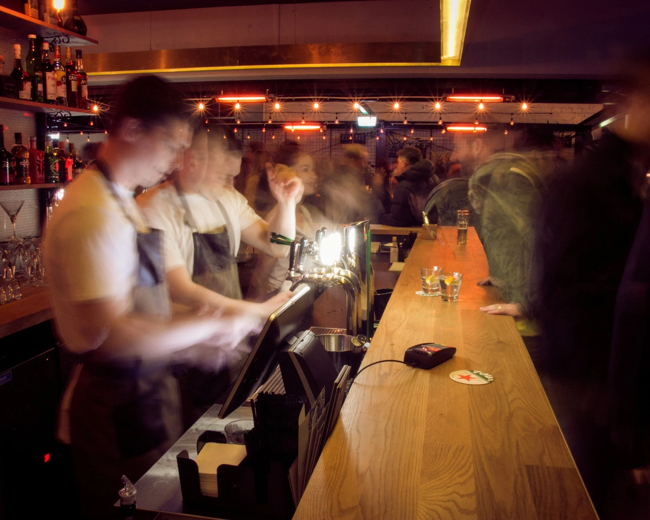 Bartenders pouring drinks at the busy bar on a lively evening