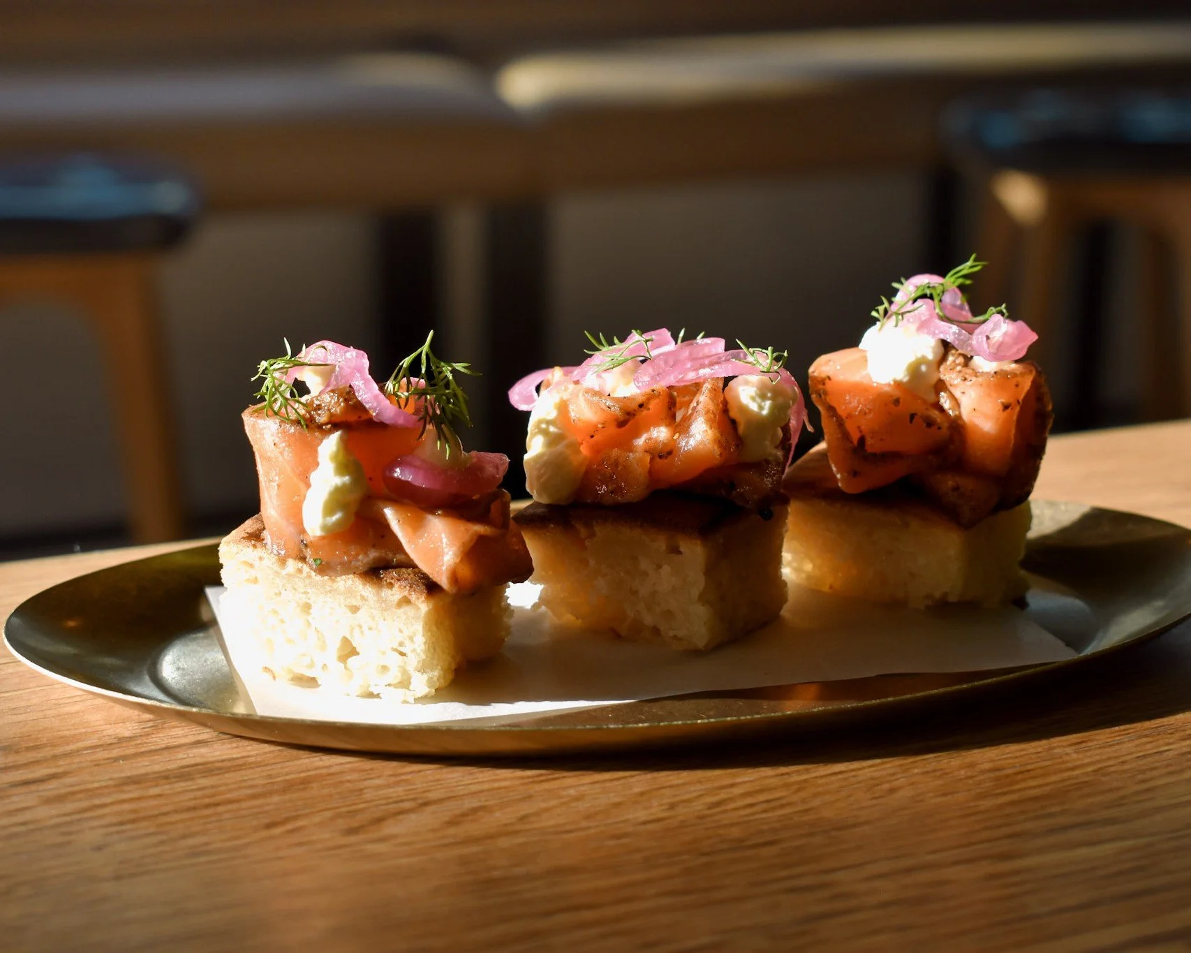 Smoked salmon canapés on focaccia with pickled onion and dill, plated in sunlight