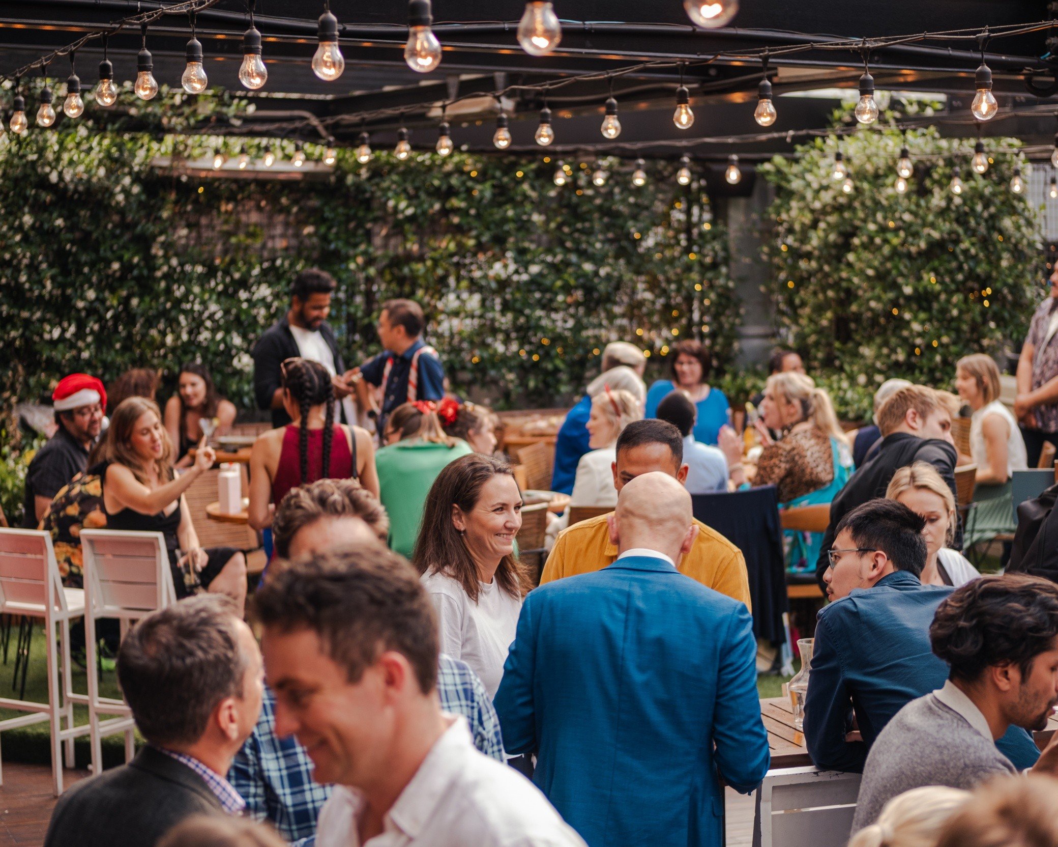 Guests celebrating at a Christmas party under festoon lights on the rooftop terrace