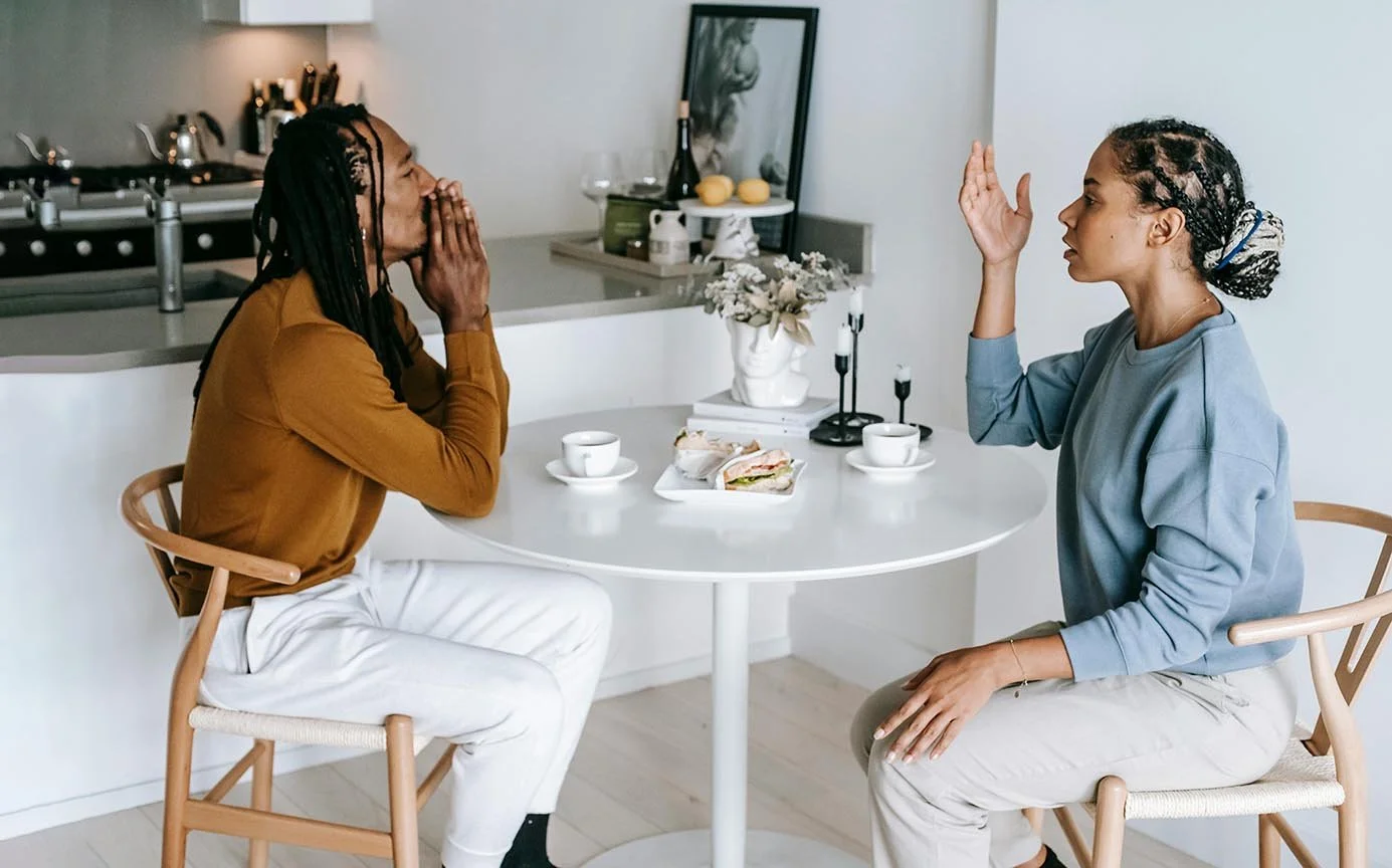 married expat couple having difficult conversation at round table near their kitchen