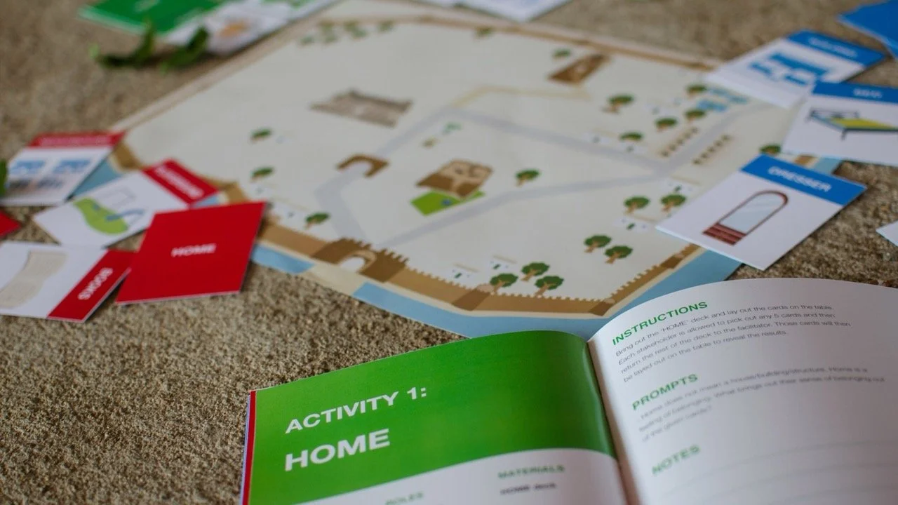 A board game about a house with activity and instruction sheets, along with various cards and game pieces, is laid out on a textured surface.