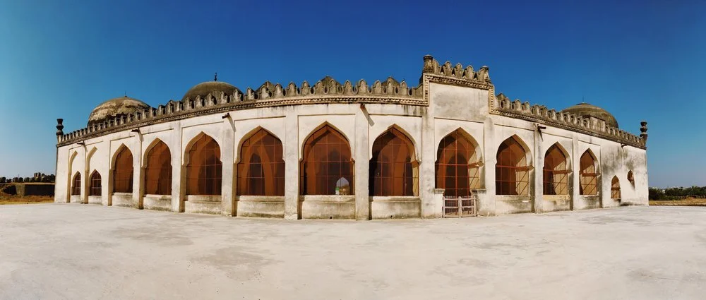 A historic building with arched windows and domed roofs, surrounded by an open courtyard.