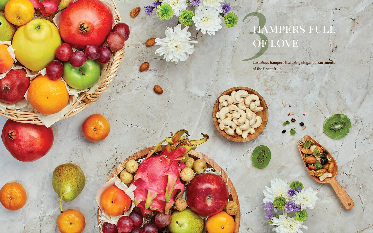 A flat lay of fresh fruits including apples, oranges, grapes, a pear, pomegranate, dragon fruit, and a basket of mixed fruits on a marble surface, with nuts and flower decorations, and a text overlay that reads 'Hampers Full of Love'.