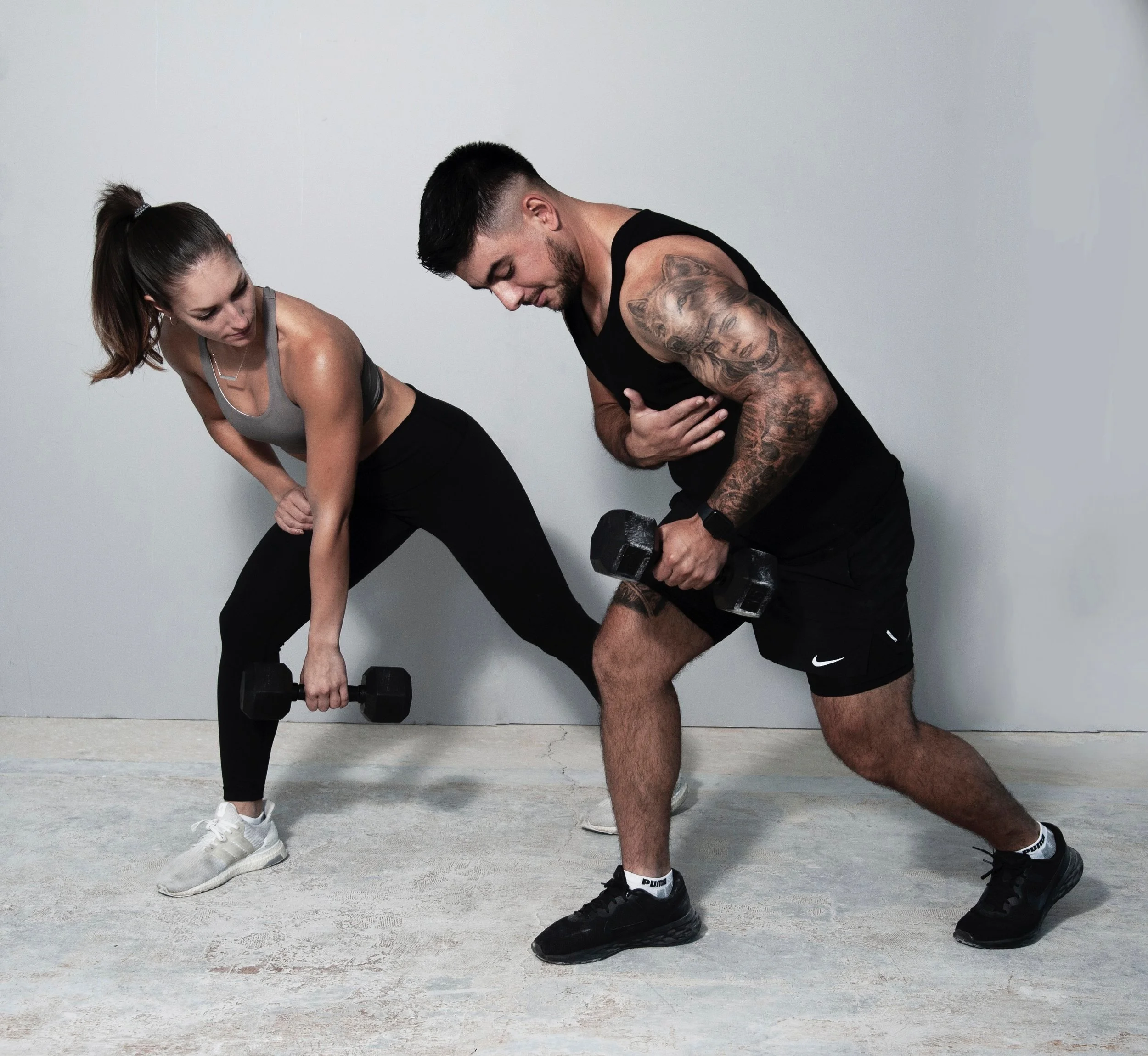 Man and woman performing a workout with dumbbells, in a gym or fitness setting.
