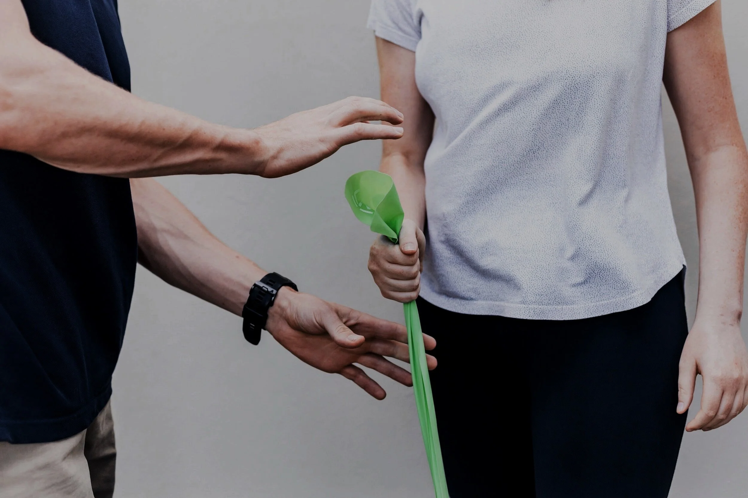 Two people exchanging a green balloon, one holding it and the other reaching out to take it.