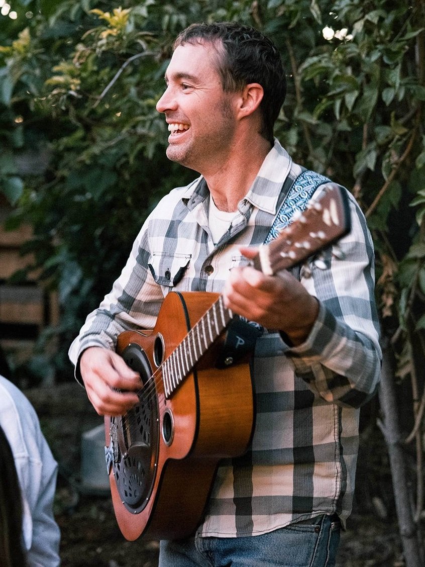 Marcus Marianthi smiles while playing the guitar