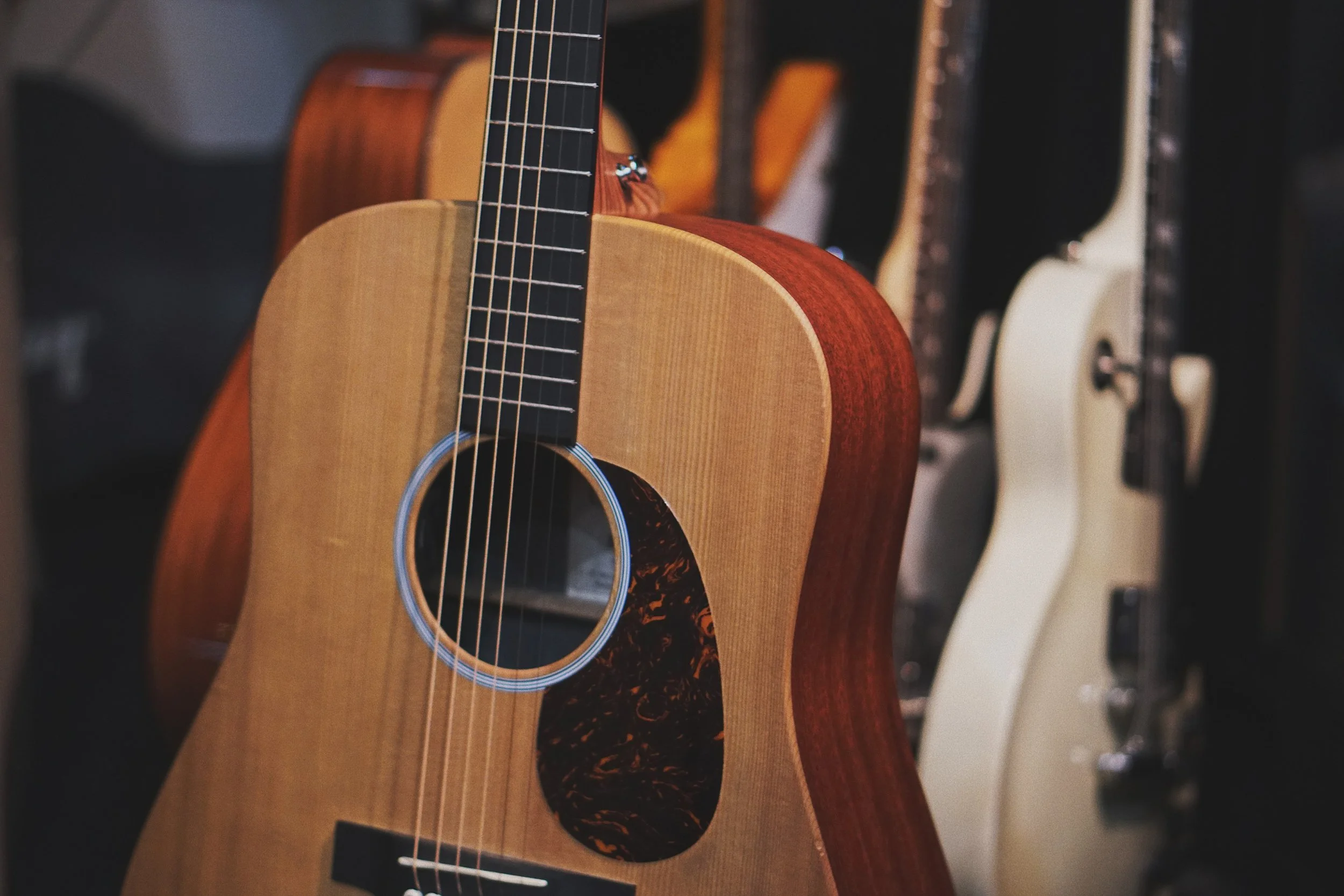 Closeup of an acoustic guitar with other guitars in the background