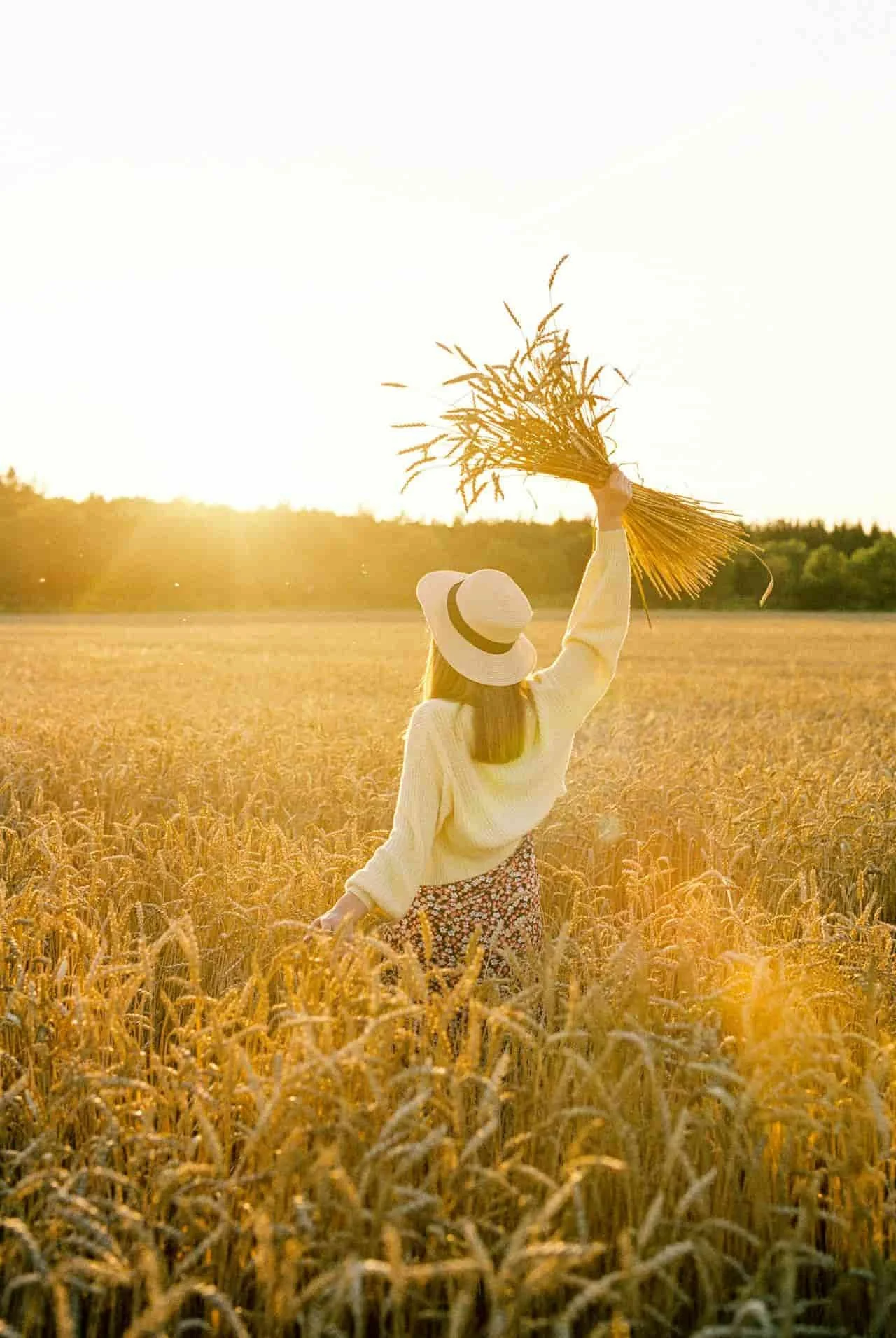 woman in field holding up a handful of wheat
