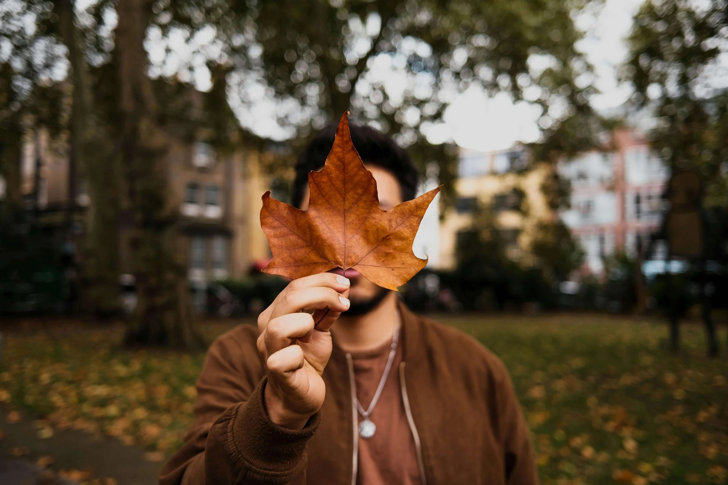 Man holding orange leaf in front of his face
