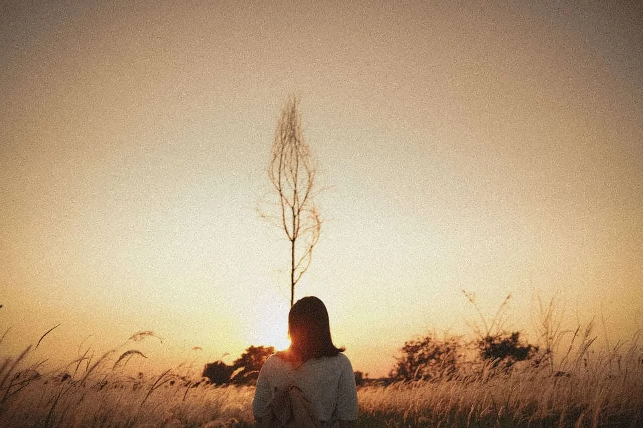woman standing in front of tree at dusk