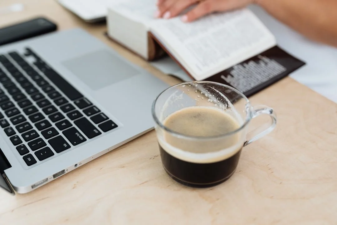 reading the bible with coffee and a laptop
