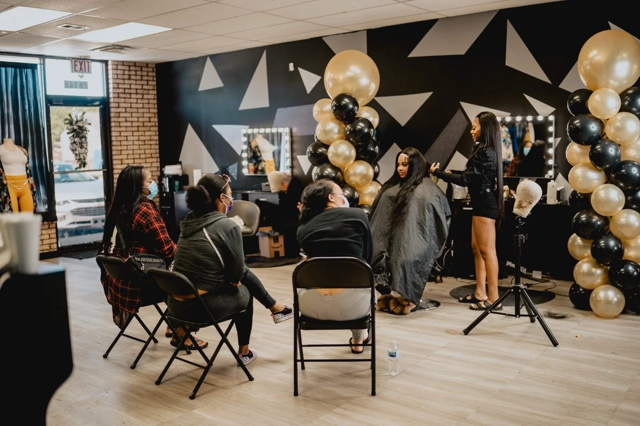 Kaniya J, a Detroit hairstylist, teaching a hair class to a full room