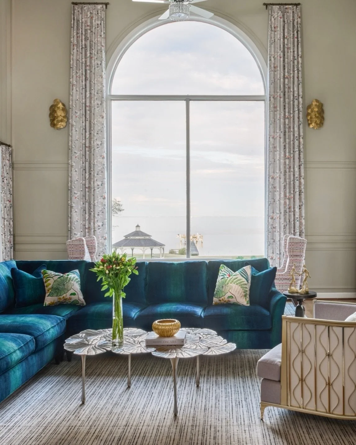 This great room shines with a statement bold blue sofa, gold-accented wall sconces and chairs, and expansive windows framing a serene water view. Sophisticated, vibrant, and effortlessly inviting.

#lornagrossinteriordesign #lornagross#holidayseason 