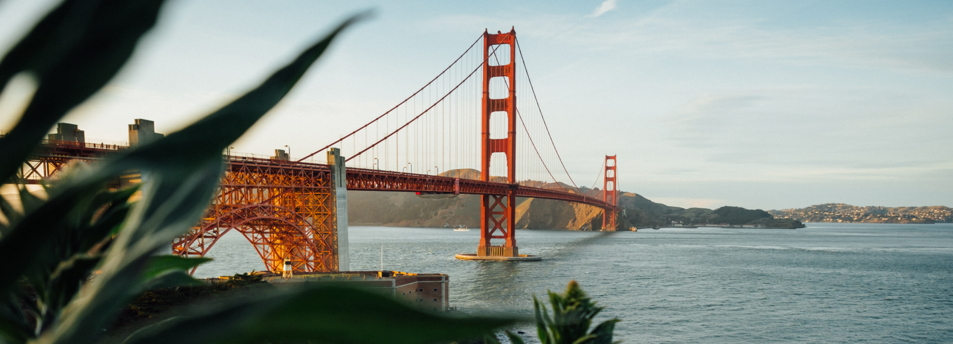 The Golden Gate Bridge in San Francisco is seen from the short with bright red hues and deep blues and greens.