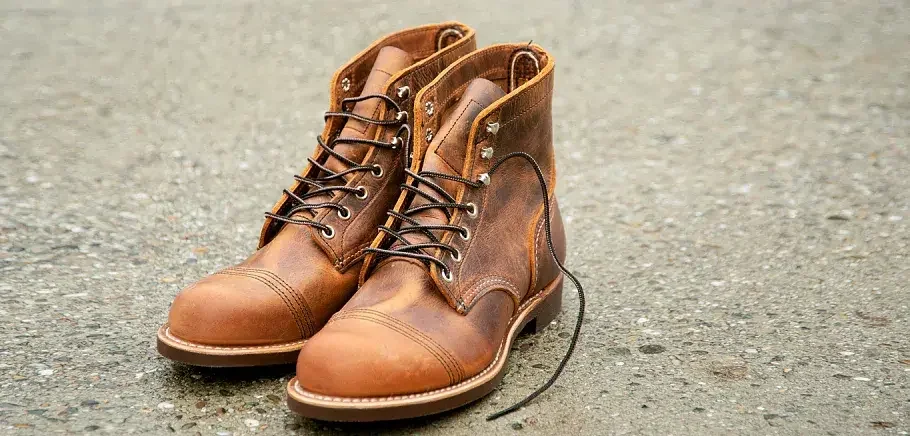 A pair of brown Red Wing leather boots with yellow laces and white soles on a plain background.