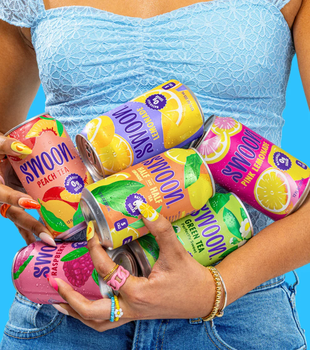 A person wearing a light blue lace top and blue jeans holds several cans of Sparkling Water with Lemon, Peach Tea, Pink Lemonade, Green Tea, and Raspberry flavors against a bright blue background.