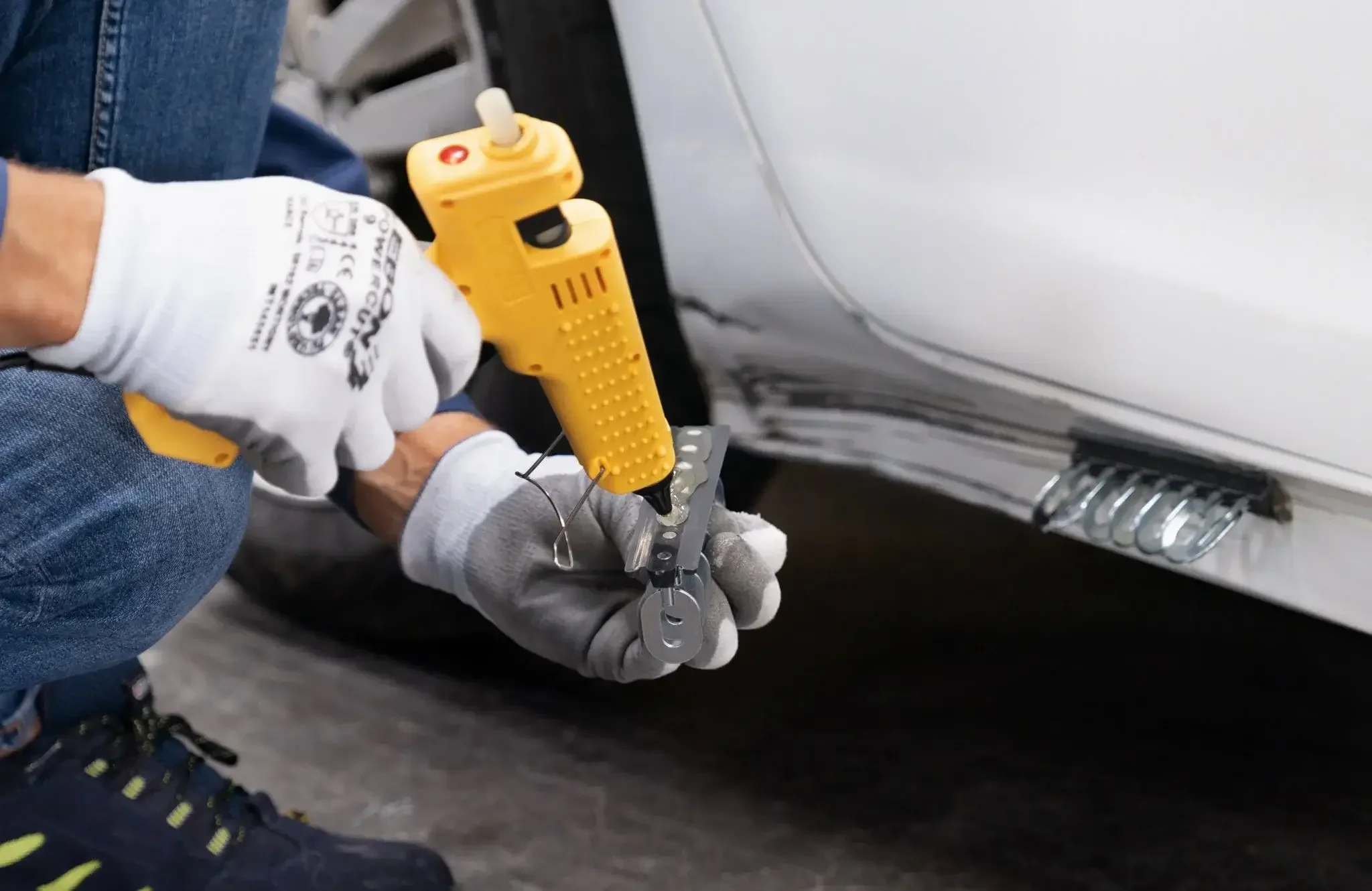 Man using gys glue pull gun to fix a dent in a collision repair shop
