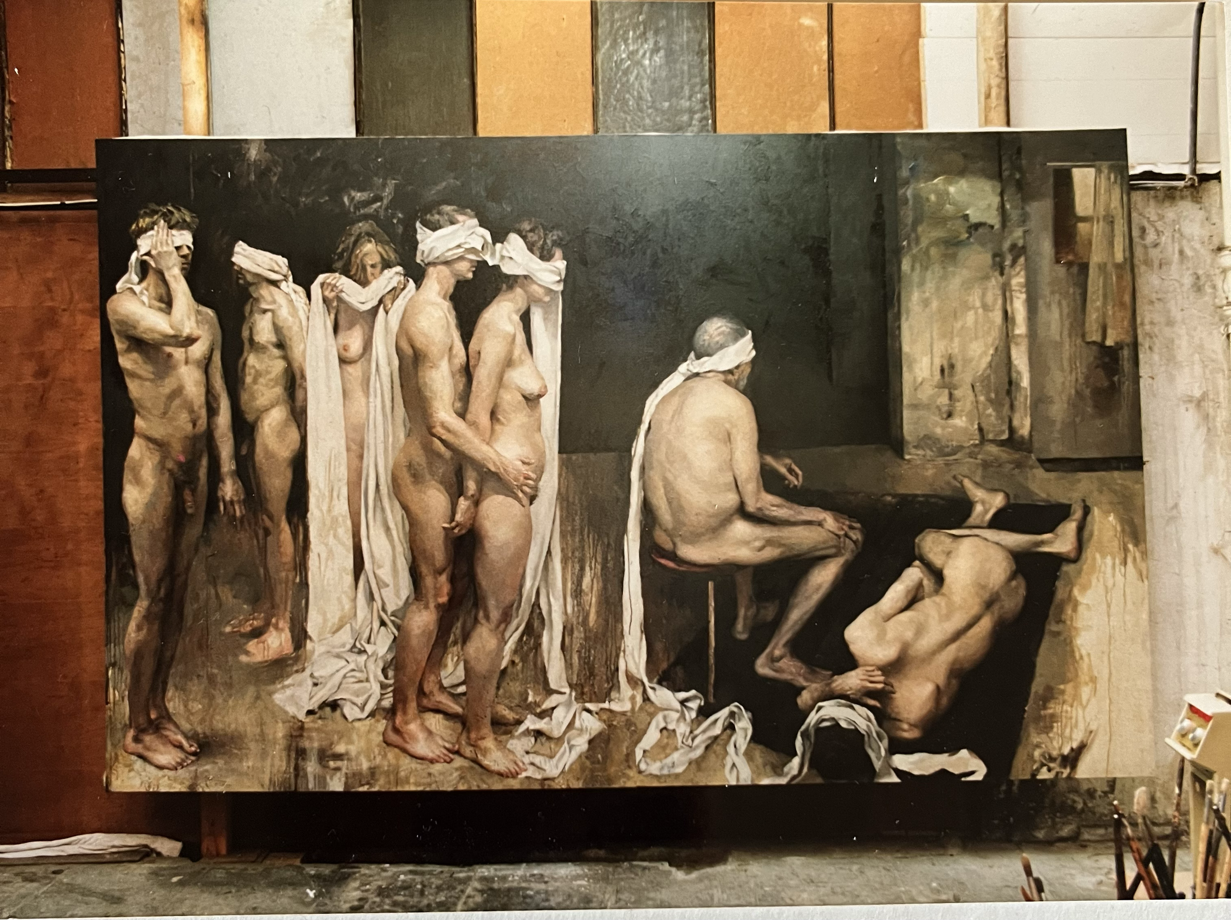 A large painting depicting a group of nude women standing in line with white cloths over their eyes, and two nude men seated and lying down, with a dark background and textured walls surrounding the scene.